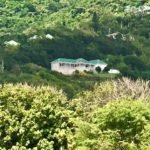 Secluded hillside property with lush greenery and a modern house, perfect for luxury real estate in Nevis by 17 Degrees North Realtors.