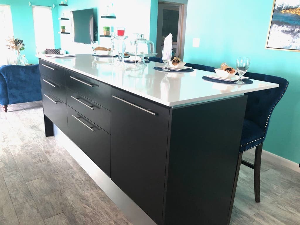 Contemporary kitchen island with sleek black cabinetry, white countertop, and elegant table setting in a modern home, highlighting upscale interior design in Evis.