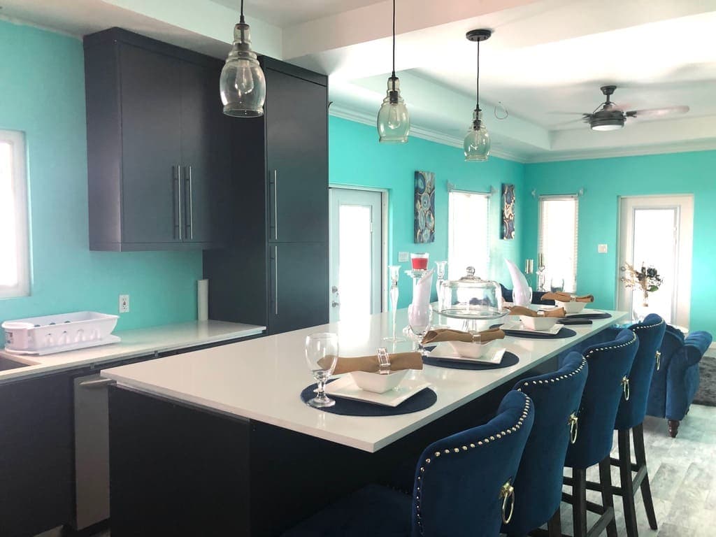 Modern kitchen with turquoise walls, black cabinetry, and stylish bar seating, perfect for homebuyers viewing Nevis real estate from 17 Degrees North Realtors.