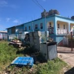 Colorful blue house with white balcony railings in a tropical neighborhood, showcasing real estate options in Evits, perfect for buyers seeking mountain views and modern home designs.