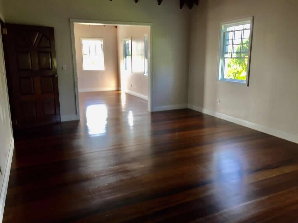Spacious living room with hardwood floors and large windows in a modern home near 17 Degrees North, Evisting, showcasing beautiful natural light and stylish interior design.