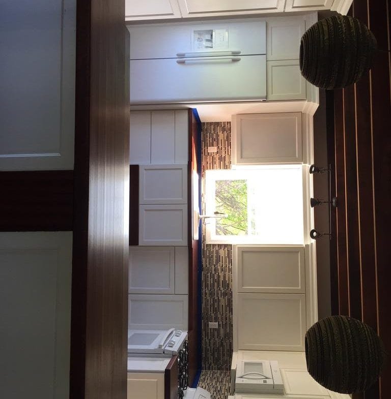 Bright modern kitchen with white cabinets, dark wooden countertops, mosaic backsplash, and large window in Nevu00eds, featuring stainless steel appliances and high-quality finishes.