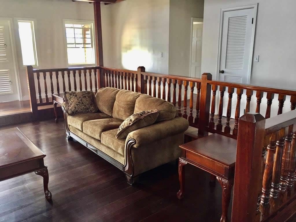 Cozy living room with hardwood floors, wooden railing, beige sofa, and classic furniture, perfect for a residential home in Evis, Florida.