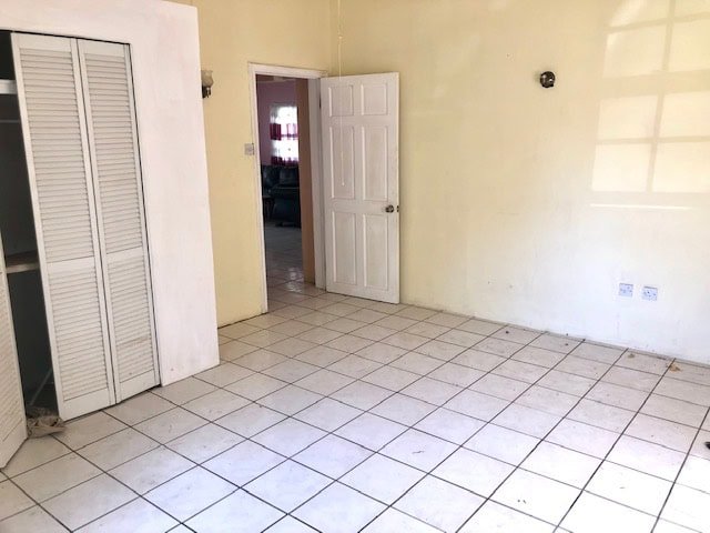 Spacious empty room with tiled flooring and open door, ideal for real estate listings and property showcasing in Evis by 17 Degrees North Realtors.