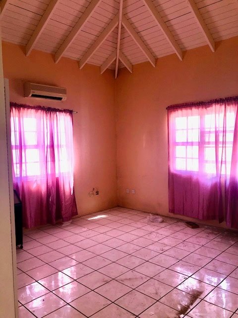 Brightly lit room with pink curtains, tiled floor, and vaulted ceiling, ideal for homebuyers seeking spacious and luminous interiors in Nevis.