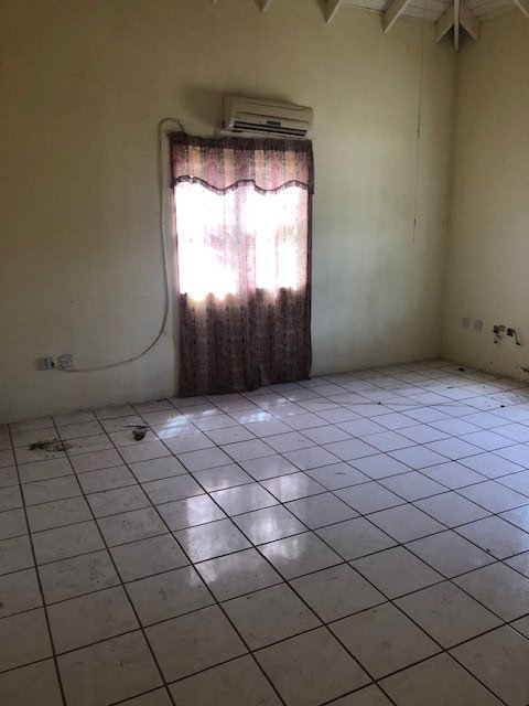 Dilapidated room with dirty tiled floor, window with curtains, and air conditioning unit, listing property for sale or rent through 17 Degrees North Realtors.