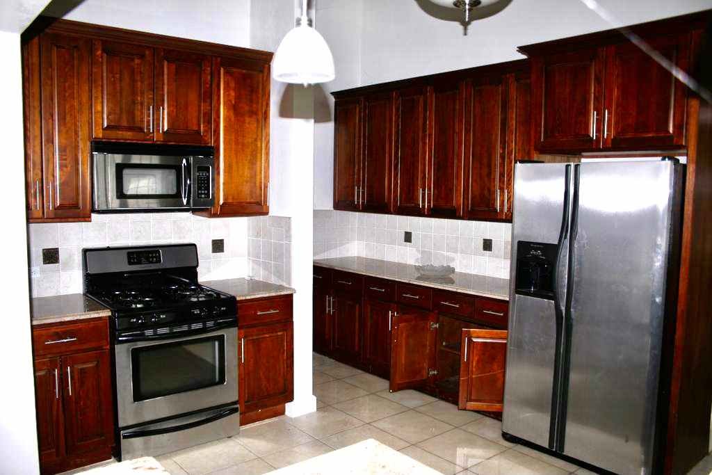 Spacious kitchen with dark wood cabinets and stainless steel appliances, including a microwave, oven, and refrigerator, ideal for modern home living in Evis.