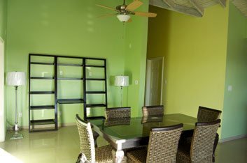Modern dining room with lime green walls, stylish wood furniture, and contemporary lighting, perfect for hosting or relaxing in a vibrant, renovated home.