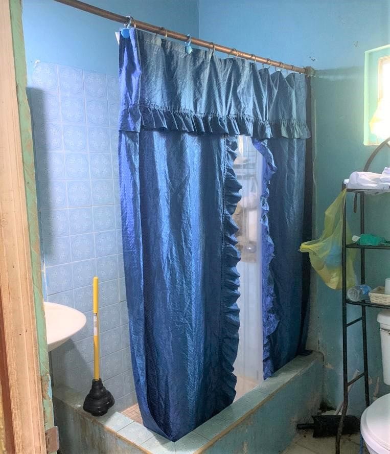 BN22 Molyneux Housing Development 7 Blue shower curtain in small bathroom with blue tile walls and green walls, compact shower area, basic bathroom setup, residential real estate description, 17 Degrees North Realtors.