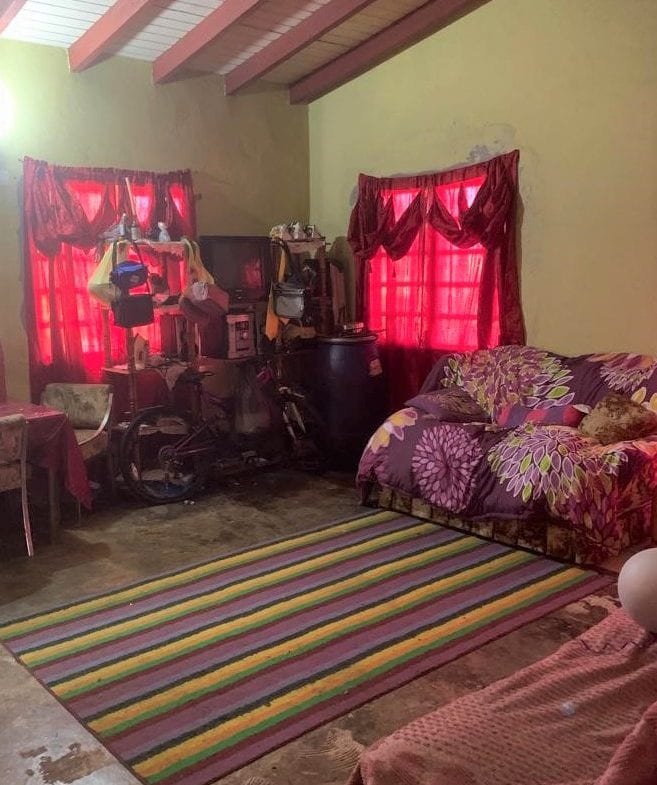 Cluttered living room with red curtains and floral sofa in a home listed by 17 Degrees North Realtors.