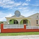 Modern single-family home with spacious front yard, satellite dish, and vibrant exterior paint, located in a scenic neighborhood ideal for real estate investment and family living.