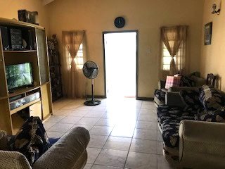 Living room with natural light, beige walls, and comfortable seating in a family home in Navasota, Texas. Great space for relaxation and gatherings, featuring a TV, fans, and cozy decor.