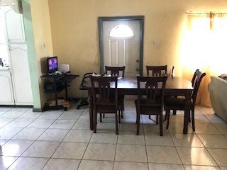 Modern dining area in a home near 17 Degrees North Realtors, featuring a wooden dining table with six chairs, a small television, and bright natural lighting for a cozy living space.