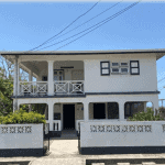 17 Degrees North Realtors property listing featuring a two-story home with a spacious balcony, white exterior, and tropical landscaping, ideal for homebuyers seeking Bahamas real estate opportunities.