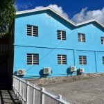 Colorful blue residential building with multiple windows and air conditioning units, located in Evis, showcasing prime real estate listings by 17 Degrees North Realtors.