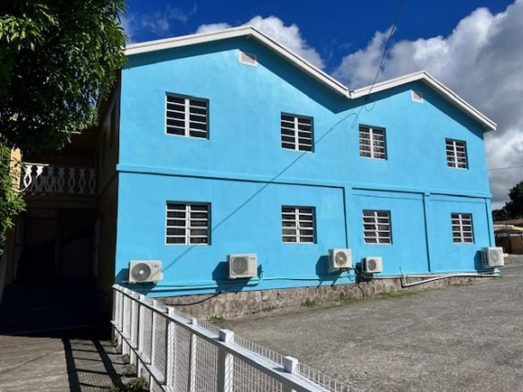 Colorful blue residential building with multiple windows and air conditioning units, located in Evis, showcasing prime real estate listings by 17 Degrees North Realtors.