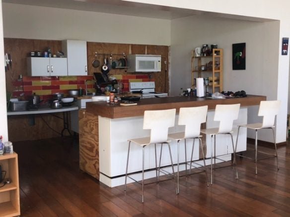 Modern kitchen with white cabinets, colorful tile backsplash, and a breakfast bar with four white chairs, perfect for homebuyers seeking contemporary real estate in Evnis.