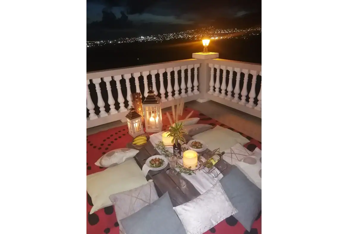Cozy outdoor rooftop dining setup at 17 Degrees North Realtors, overlooking city lights at night with lanterns, candles, and a beautiful sunset view, perfect for romantic dinners or relaxing evenings.