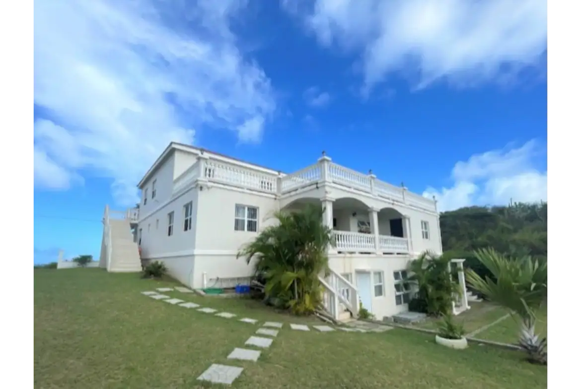 Luxury white beach house with ocean views, spacious balconies, tropical landscaping, located at 17 Degrees North in Nives, perfect for real estate investment or seaside living.
