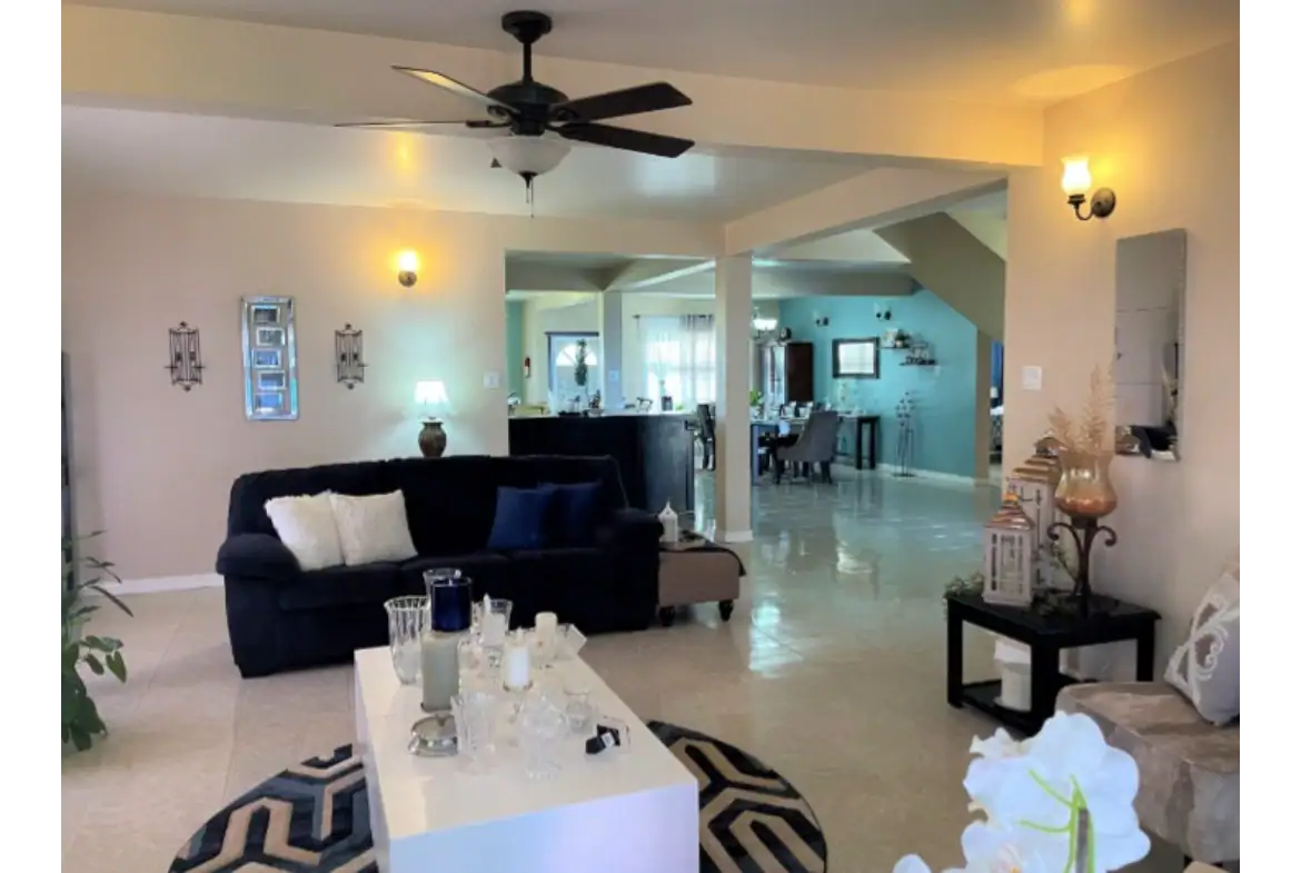 Spacious living room with modern decor, ceiling fan, and opening to dining area in a beautiful N.E.vis home listed by 17 Degrees North Realtors.