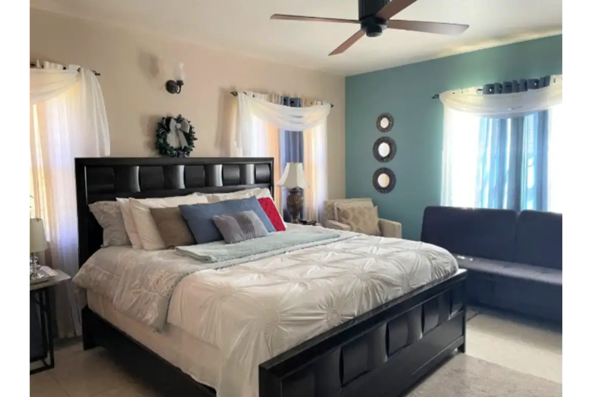 Bright master bedroom with large bed, stylish decor, and natural light, showcasing desirable features of 17 Degrees North real estate properties.