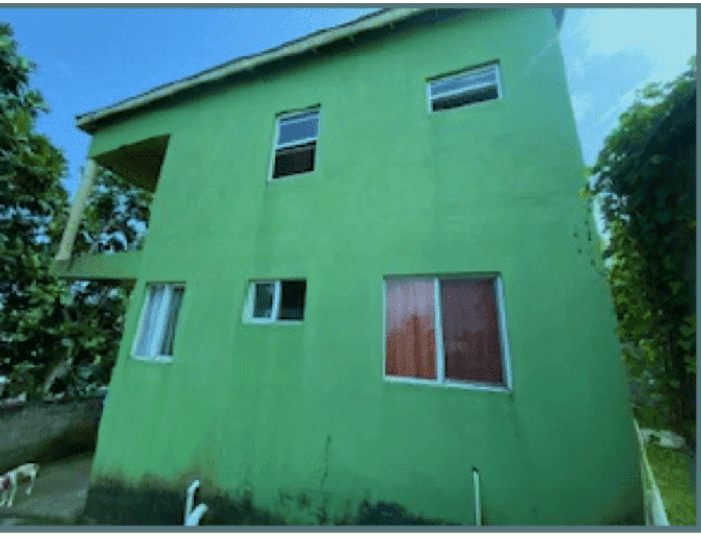 Bright green multi-story residential building with multiple windows, located in a lush environment, listed by 17 Degrees North Realtors for real estate investment and property sales.