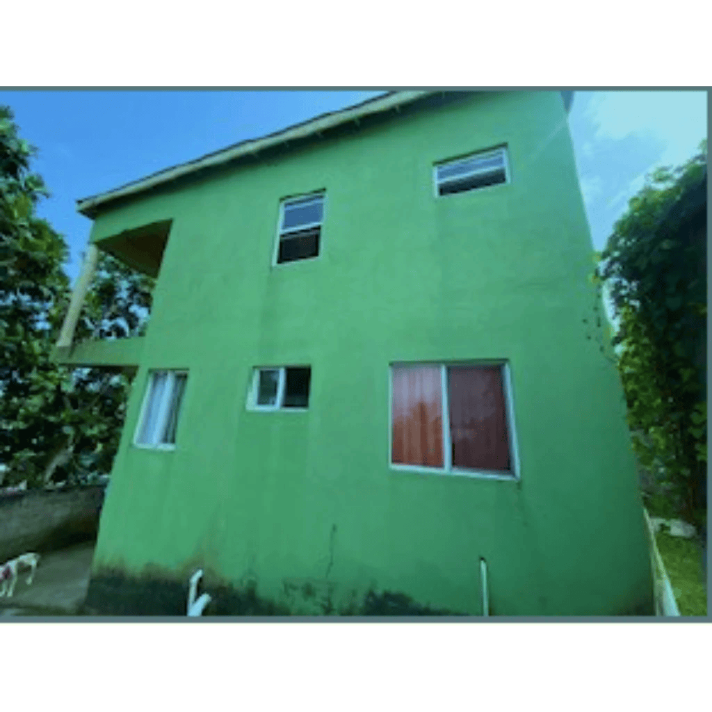 Bright green multi-story residential building with multiple windows, located in a lush environment, listed by 17 Degrees North Realtors for real estate investment and property sales.