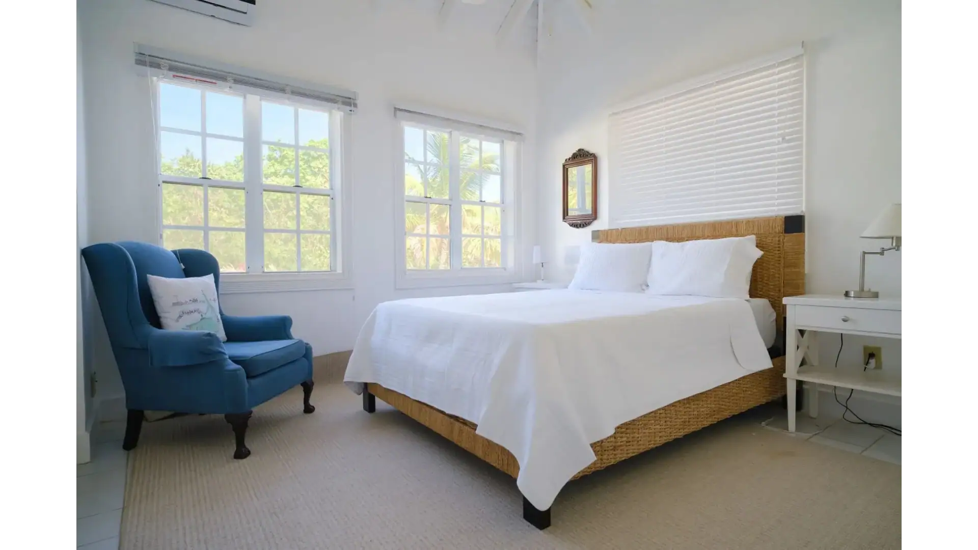 Bright and airy bedroom at 17 Degrees North Realtors, featuring large windows, white walls, and coastal-inspired decor, perfect for relaxing with a tropical view.