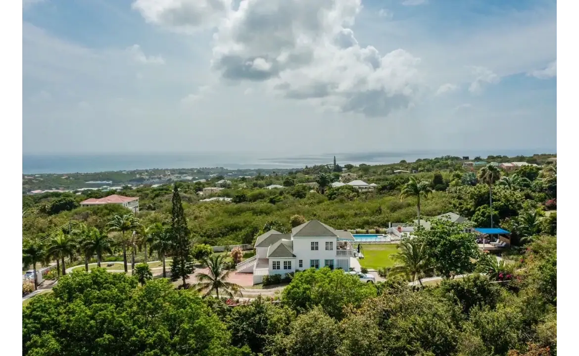 Luxurious ocean-view home surrounded by lush greenery with palm trees, beautiful gardens, and a private pool in a tropical estate. Perfect for relaxing and enjoying the scenic landscape.