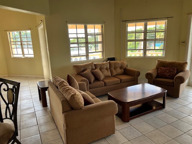 Comfortable living room with beige sectionals, plush throw pillows, and large windows offering natural light in a cozy home setting.